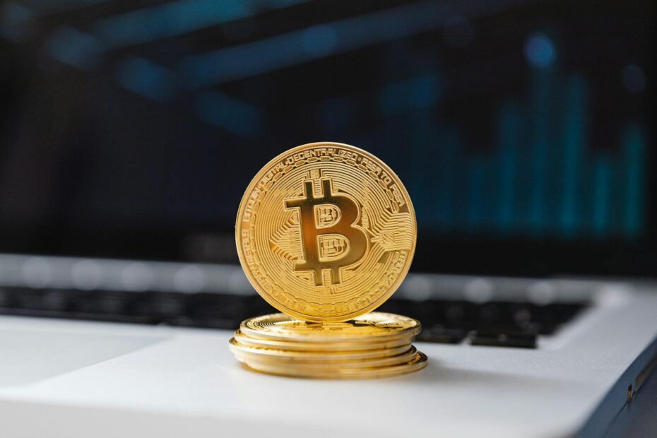 A shiny gold Bitcoin coin on laptop keyboard, symbolizing digital currency and blockchain technology.